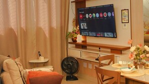 Uma sala de estar moderna com televisão de tela plana, área de jantar e sofá.