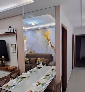 A modern living room with a sofa, a dining table with chairs, a TV, and a decorative wall. - 1503 Apto 2 Qtos completo João Pessoa (Cabedelo)