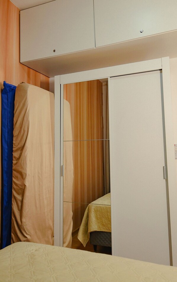 A bedroom with a bed, a wardrobe, and a curtain.