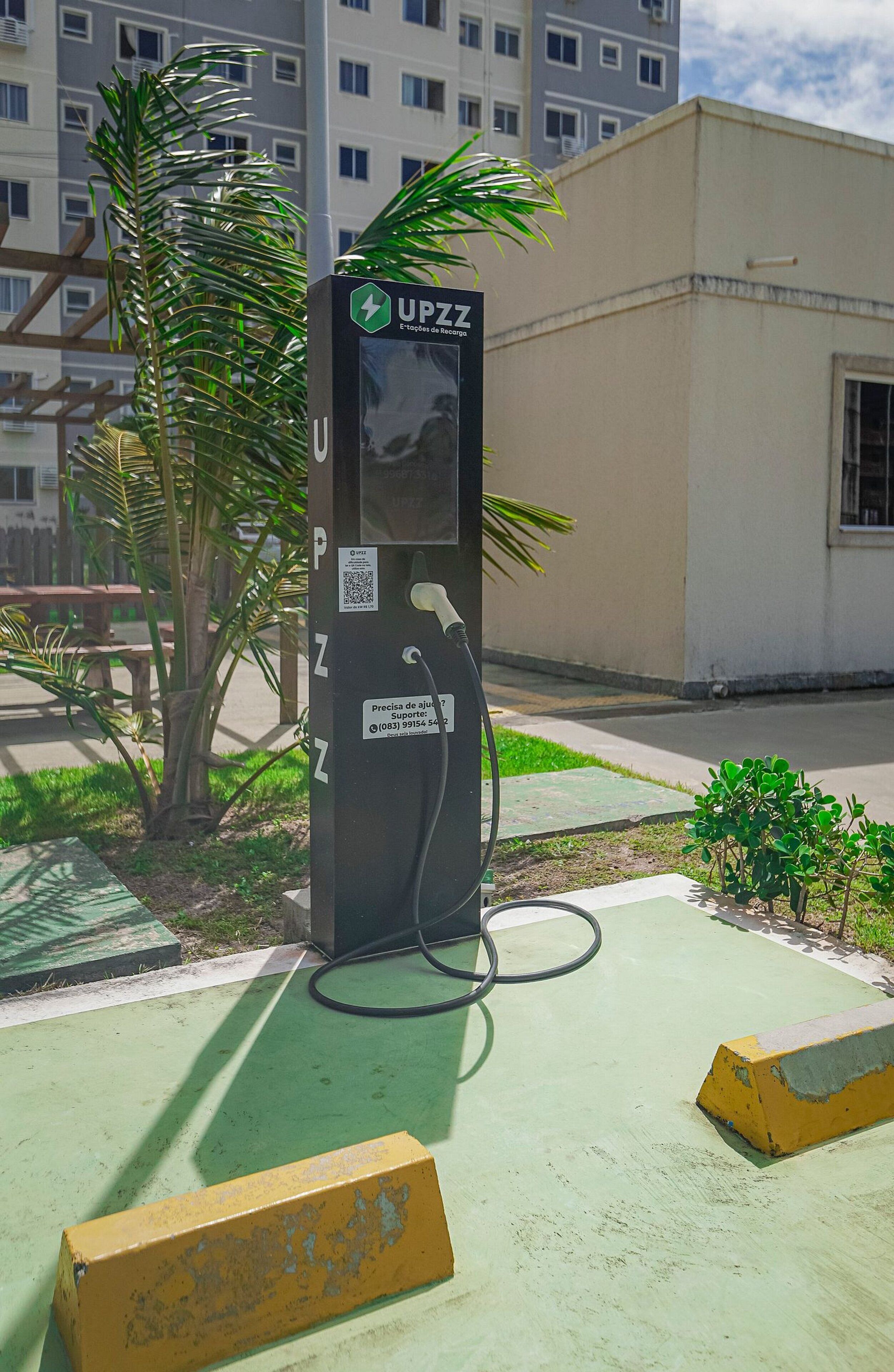 A public electric vehicle charging station with a QR code and a contact number for support.