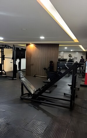A gym with exercise equipment, a wooden wall, and a seating area. - 1503 Apto 2 Qtos completo João Pessoa (Cabedelo)