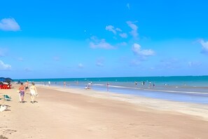 Ein Strand mit Menschen, einem klaren Himmel und ruhiger See.