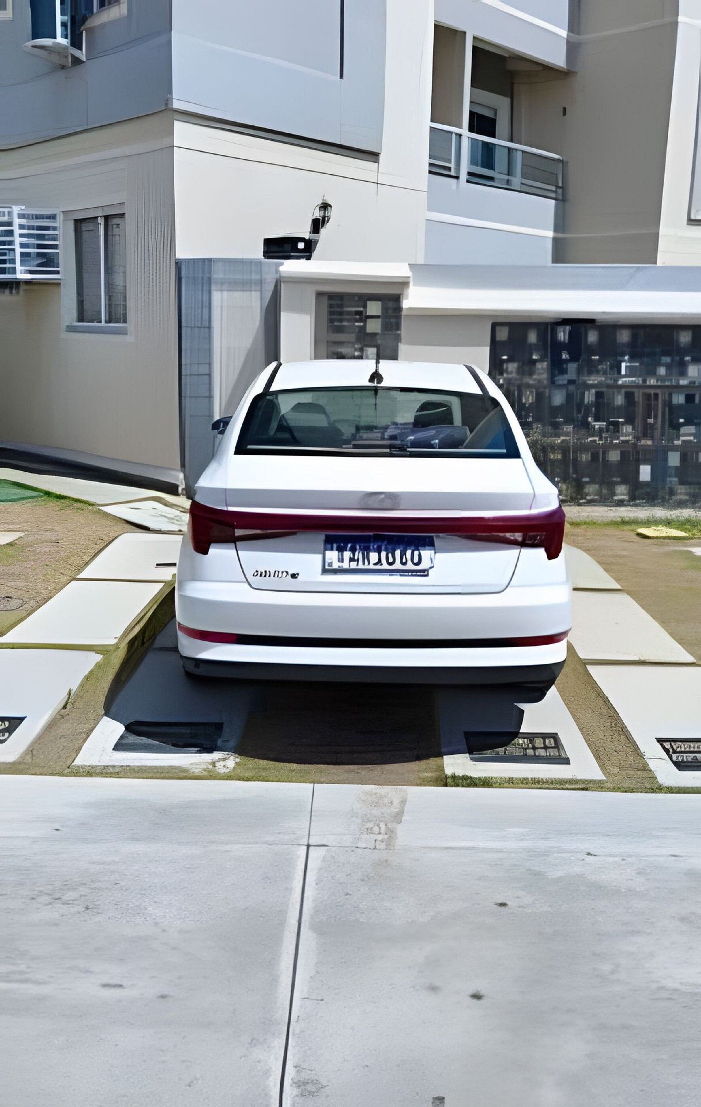 Un coche blanco estacionado en el estacionamiento de un edificio moderno.