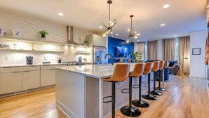 Uma cozinha moderna com uma ilha central, banquetas e iluminação pendente.
