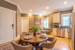 A dining area with a round table set for four, surrounded by chairs. There is a vase with flowers on the table, and a painting on the wall. - 3 BED/2 BATH- Sleeps 8 - In the heart of Cambridge - W/D (Cambridge)