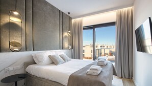 Una habitación de hotel moderna con una cama grande, vistas de la ciudad y un televisor de pantalla plana.