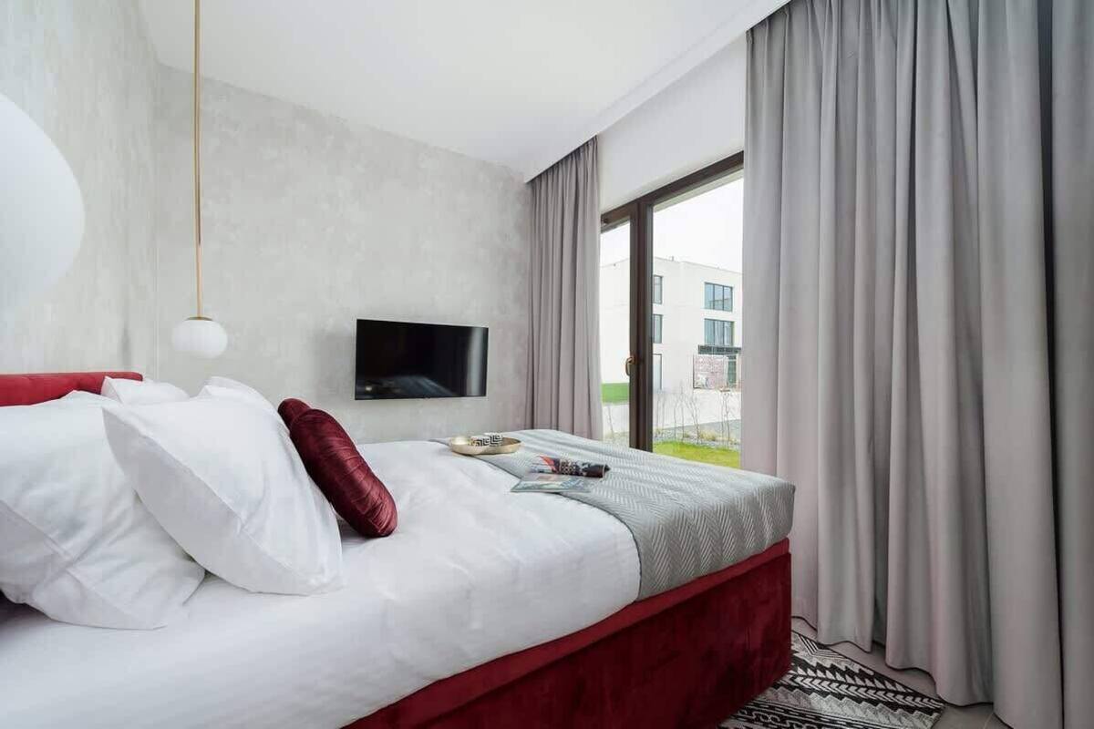 A modern hotel room with a large bed, a flat-screen TV, and a view of the outdoors.