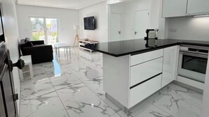 A modern kitchen with white cabinetry, a marble floor, and a built-in oven. - Quinta do Torrejão 800m plaga Armação de pêra (Porches)