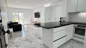 Une cuisine moderne avec des meubles blancs, un sol en marbre et un four encastré.