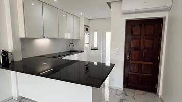Une cuisine moderne dotée d’un îlot central, de meubles blancs et d’un sol en marbre.