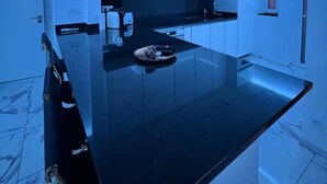 A modern kitchen with a black countertop, white cabinets, and blue ambient lighting. - Quinta do Torrejão 800m plaga Armação de pêra (Porches)