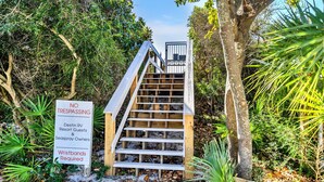 A wooden staircase leading up to a gated area with a sign prohibiting trespassing for guests and owners, and wristbands required. - Destin/Miramar Beach Escape, Family-Friendly + Private Beach Access (Destin)