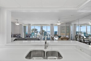 Eine moderne Küche mit einer großen Kochinsel, einer Spüle mit zwei Becken und Blick auf den Strand.