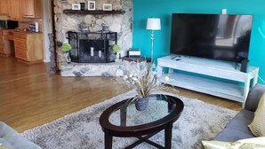Una sala de estar con chimenea de piedra, televisor de pantalla plana y sofá.