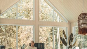 Un salon spacieux avec un haut plafond, de grandes fenêtres, une table à manger en bois et un coin salon confortable.