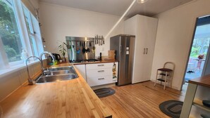 A modern kitchen with wooden countertops, stainless steel appliances, and a view of the outdoors. - Orange Grove Homestead - Spacious Garden Holiday Home (Kerikeri)