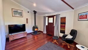 A living room with a TV, a fireplace, a sofa, and a door with curtains.
