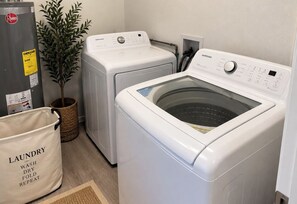 A laundry area with two front-loading washing machines, a drying machine, and a bag labeled 'laundry wash dry fold repeat'. - LUXURY POOL VILLA 5BD 4BR #3, Heated Pool (Miami)