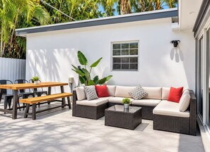 An outdoor patio with a sectional sofa, a wooden table, and chairs. - LUXURY POOL VILLA 5BD 4BR #3, Heated Pool (Miami)