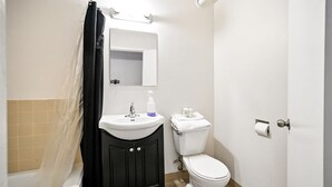 A bathroom with a white sink, black cabinets, a toilet, and a shower curtain.