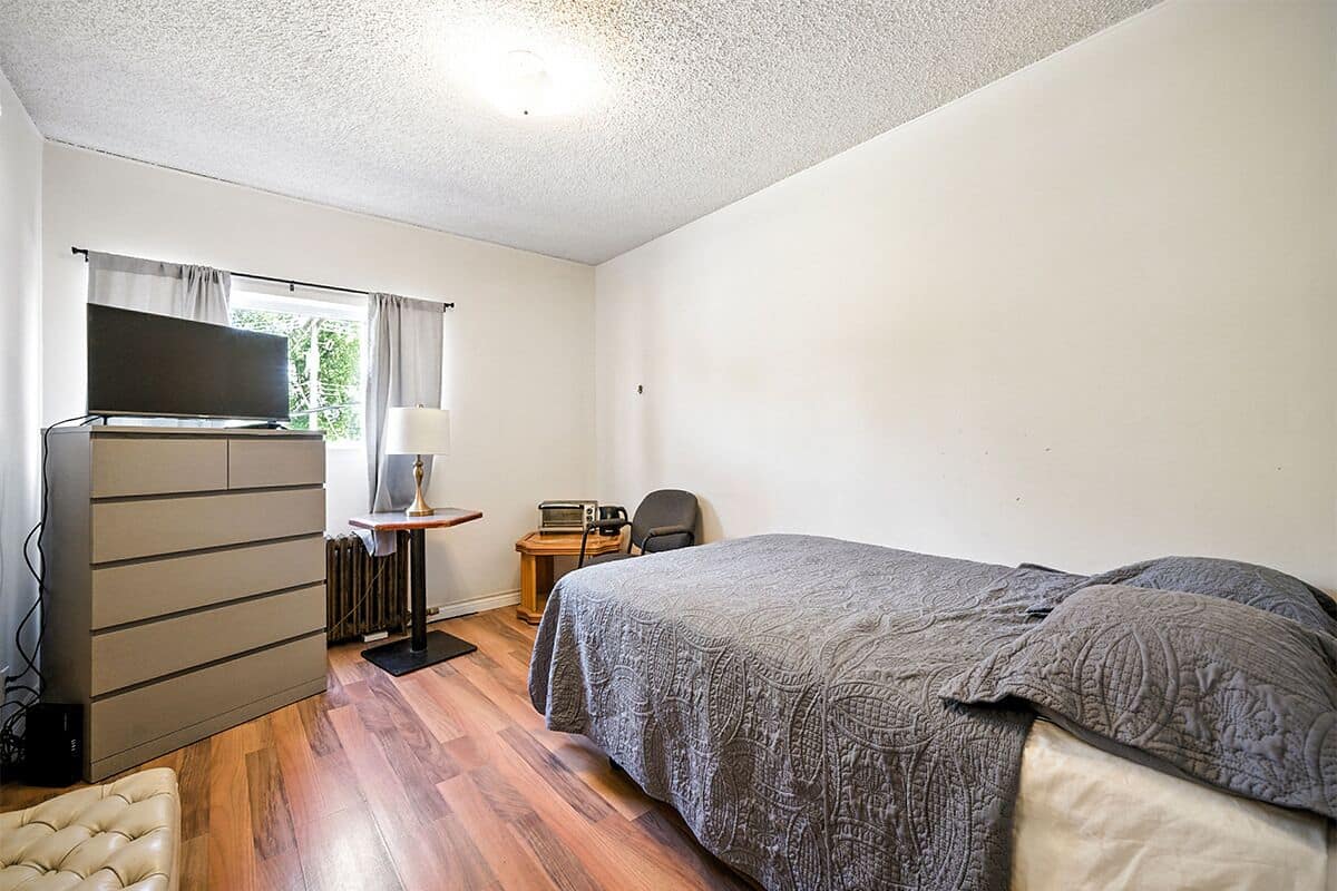 Un dormitorio con cama, escritorio, silla, televisor y armario.