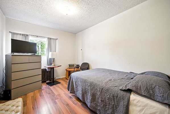 Un dormitorio con cama, escritorio, silla, televisor y armario.