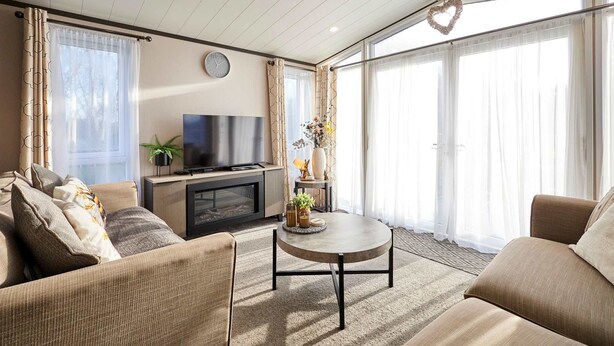 A modern living room with a sofa, coffee table, TV, and decorative items. - Host Stay Coopers Cabin (Malton)