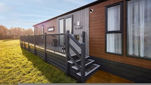 A mobile home with a porch, a staircase, and a sign indicating "Coppers Cabin." - Host Stay Coopers Cabin (Malton)