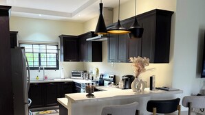 Una cucina moderna con mobili scuri, un'isola centrale con sgabelli da bar e luci a sospensione.