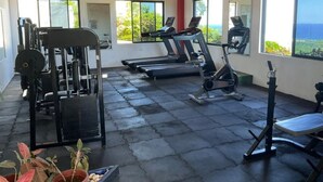 Una palestra con tapis roulant, macchinari per pesi e una panca. Dispone di ampie finestre con vista sull'esterno.