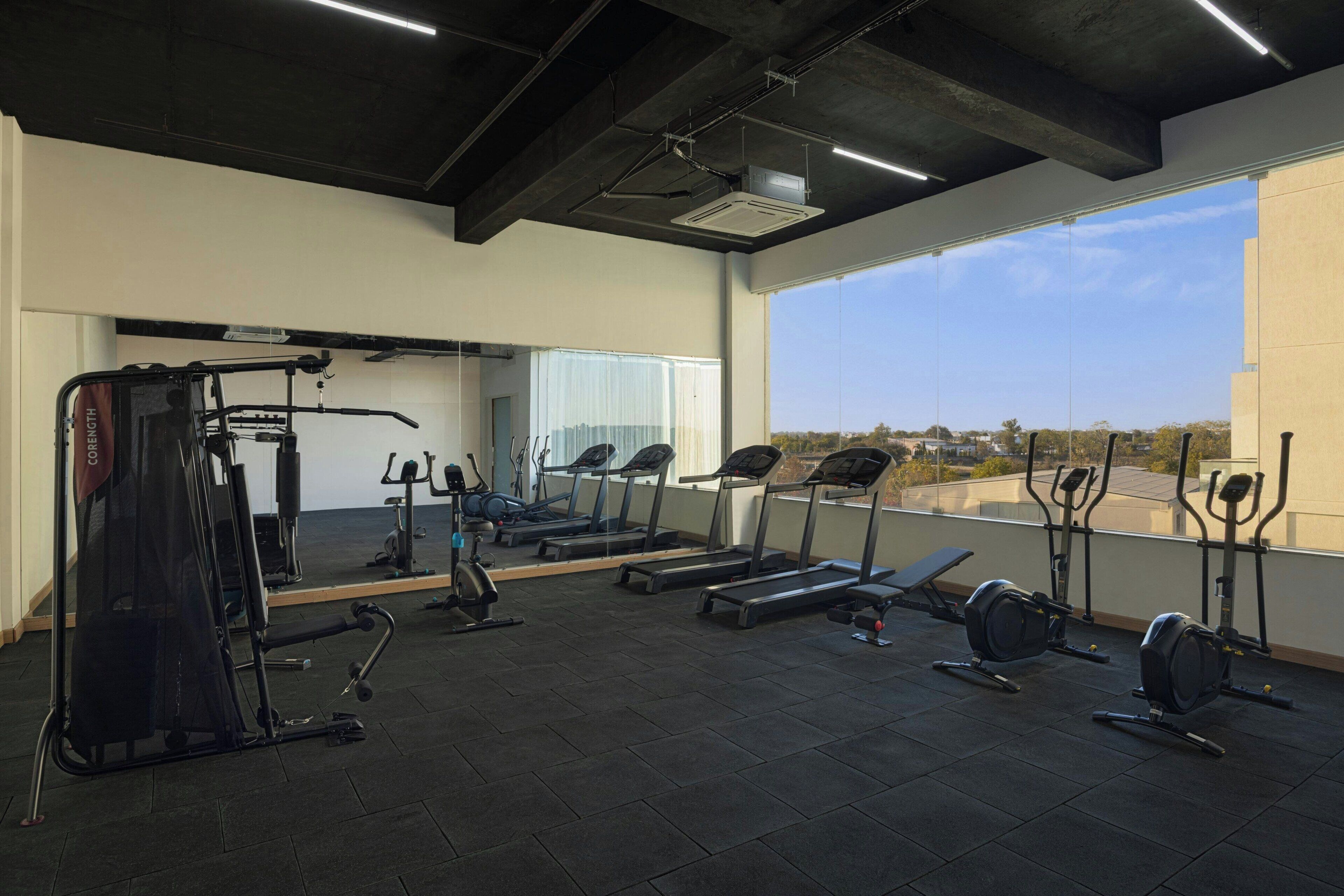 A gym with exercise equipment, a large mirror, and a view of the outdoors.