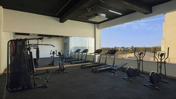 A gym with exercise equipment, a large mirror, and a view of the outdoors.