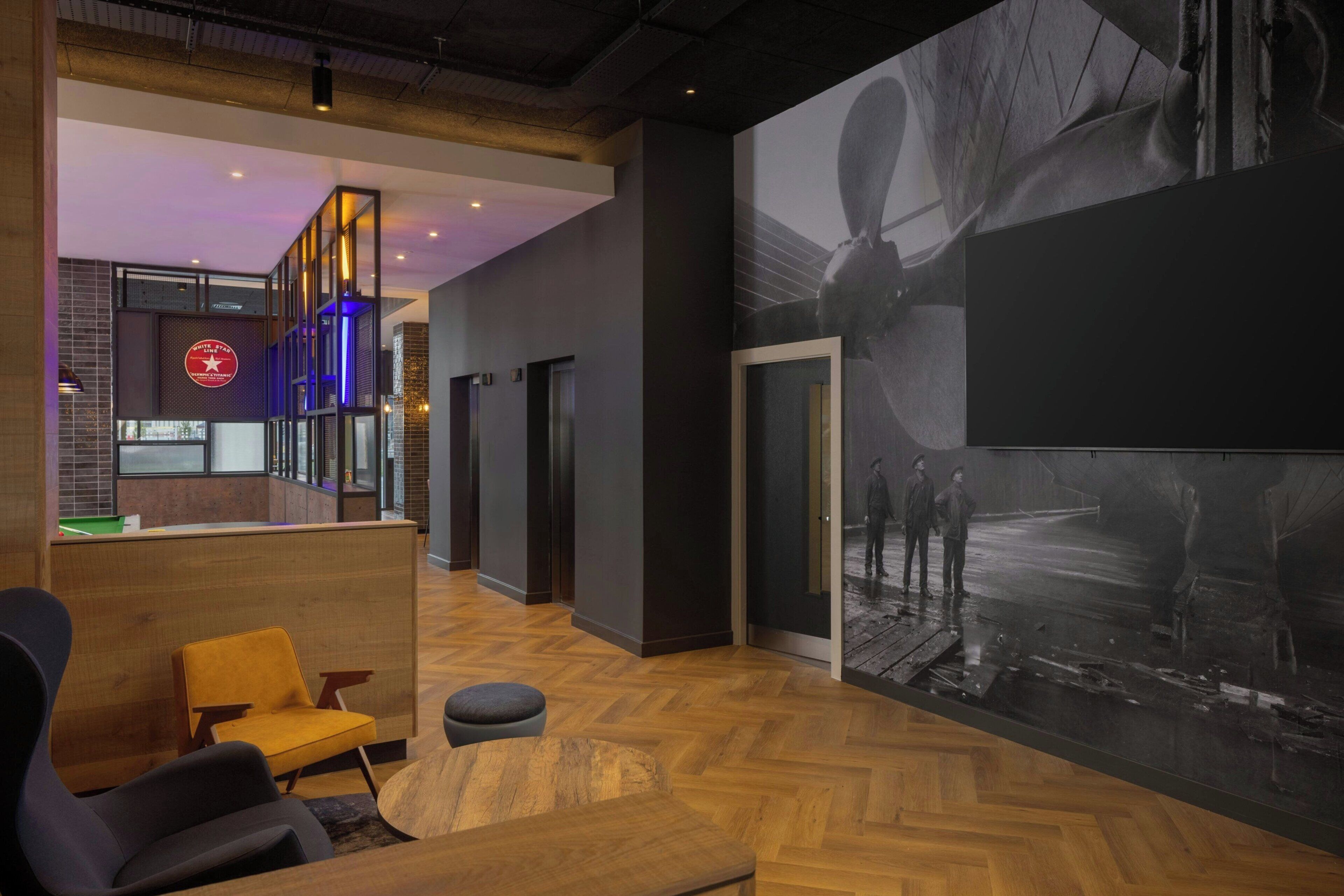 A modern lobby with a reception desk, seating area, and a large wall mural.