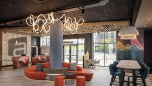 Un vestíbulo moderno con una zona de estar central, una recepción y un comedor con sillas y mesas.