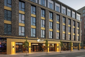 Un moderno edificio de hotel con fachada de ladrillo, ventanas amplias y un llamativo letrero de 'aloft hotels'.