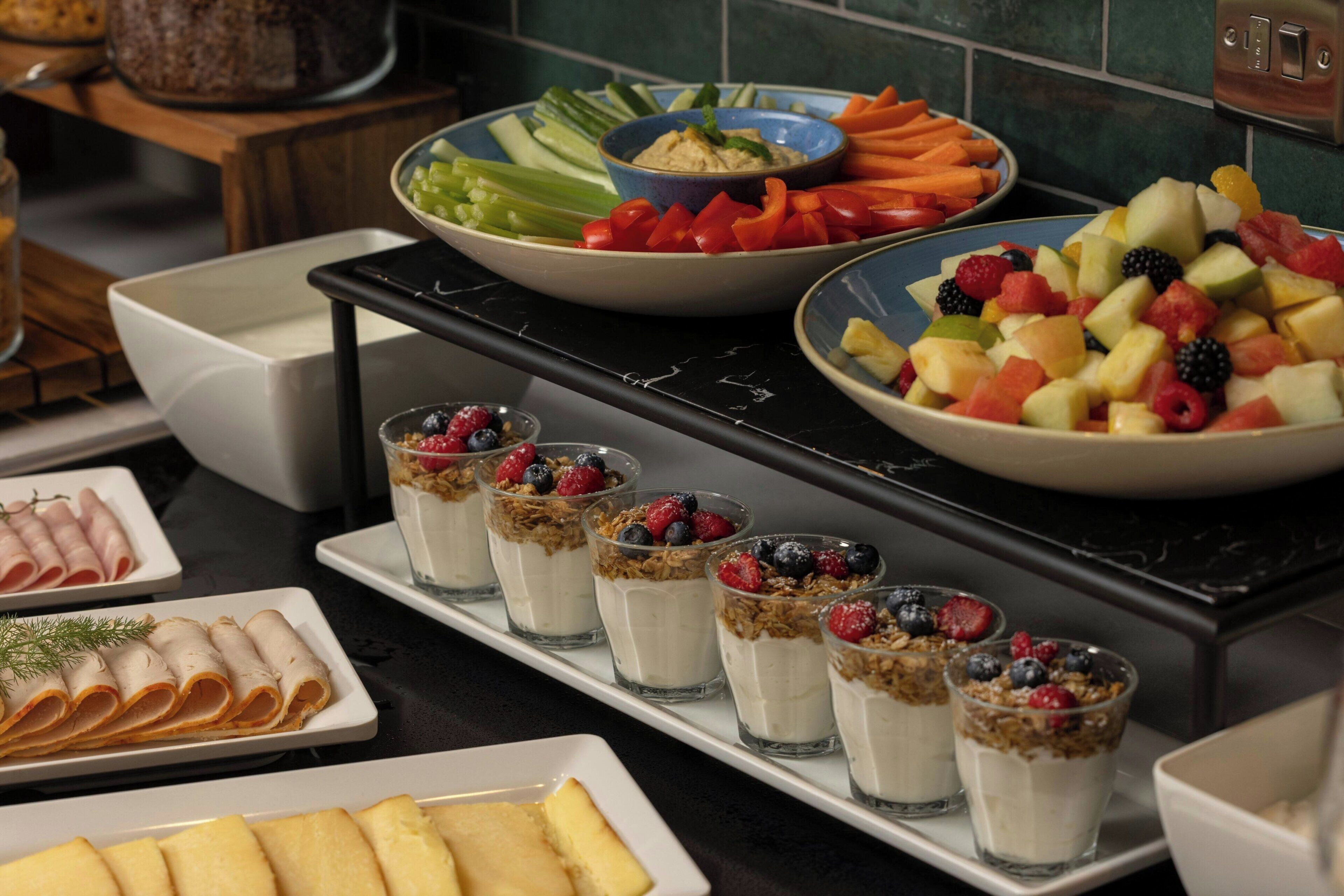 A buffet with various food items including fruits, vegetables, and a bowl of dip.
