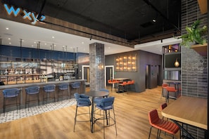 Un área de bar moderna con barra, taburetes y zona de estar con mesas y sillas.