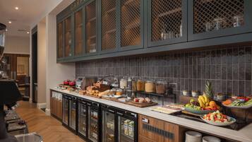 A buffet area with a variety of food items, refrigerated storage, and a coffee machine.