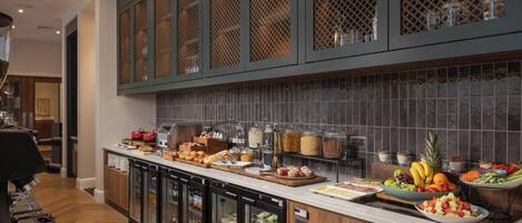 A buffet area with a variety of food items, refrigerated storage, and a coffee machine.
