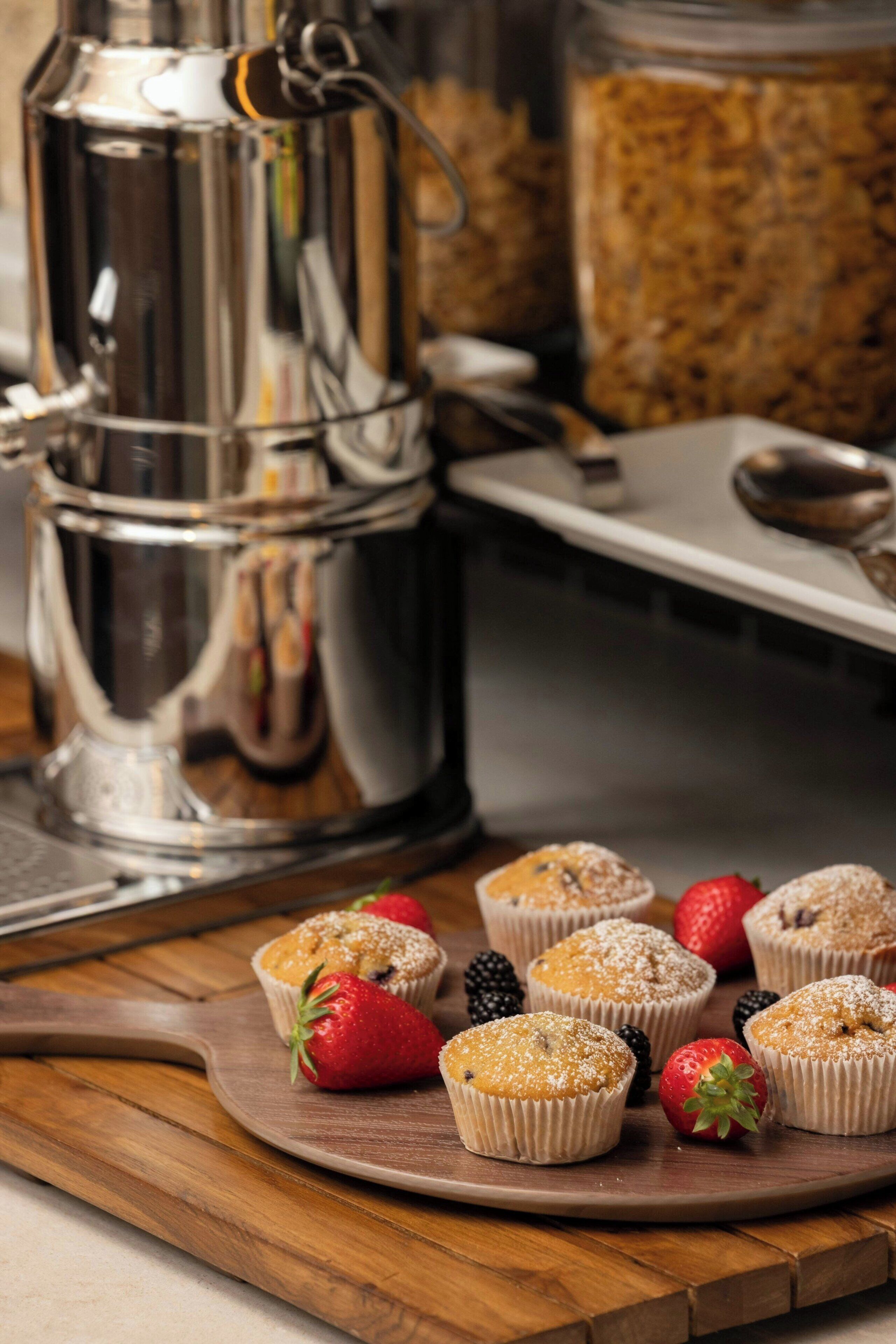Un comptoir de cuisine avec des muffins, des fraises et une machine à café.