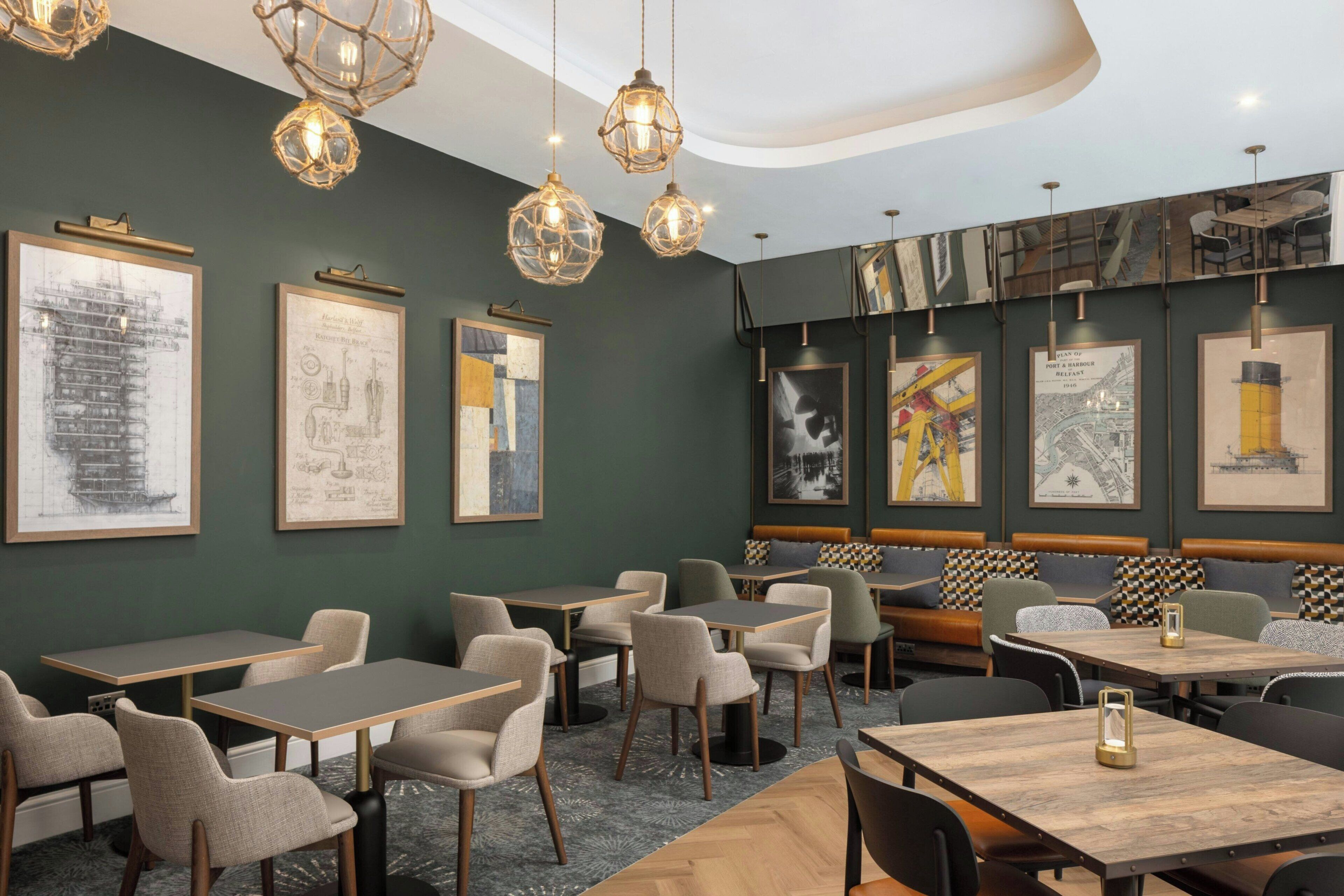A restaurant with tables and chairs, hanging lights, and framed artwork on the walls.