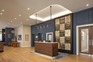A reception desk with a wooden finish, a modern pendant light, and a cityscape wall. - Residence Inn By Marriott Belfast Titanic Quarter (Belfast)