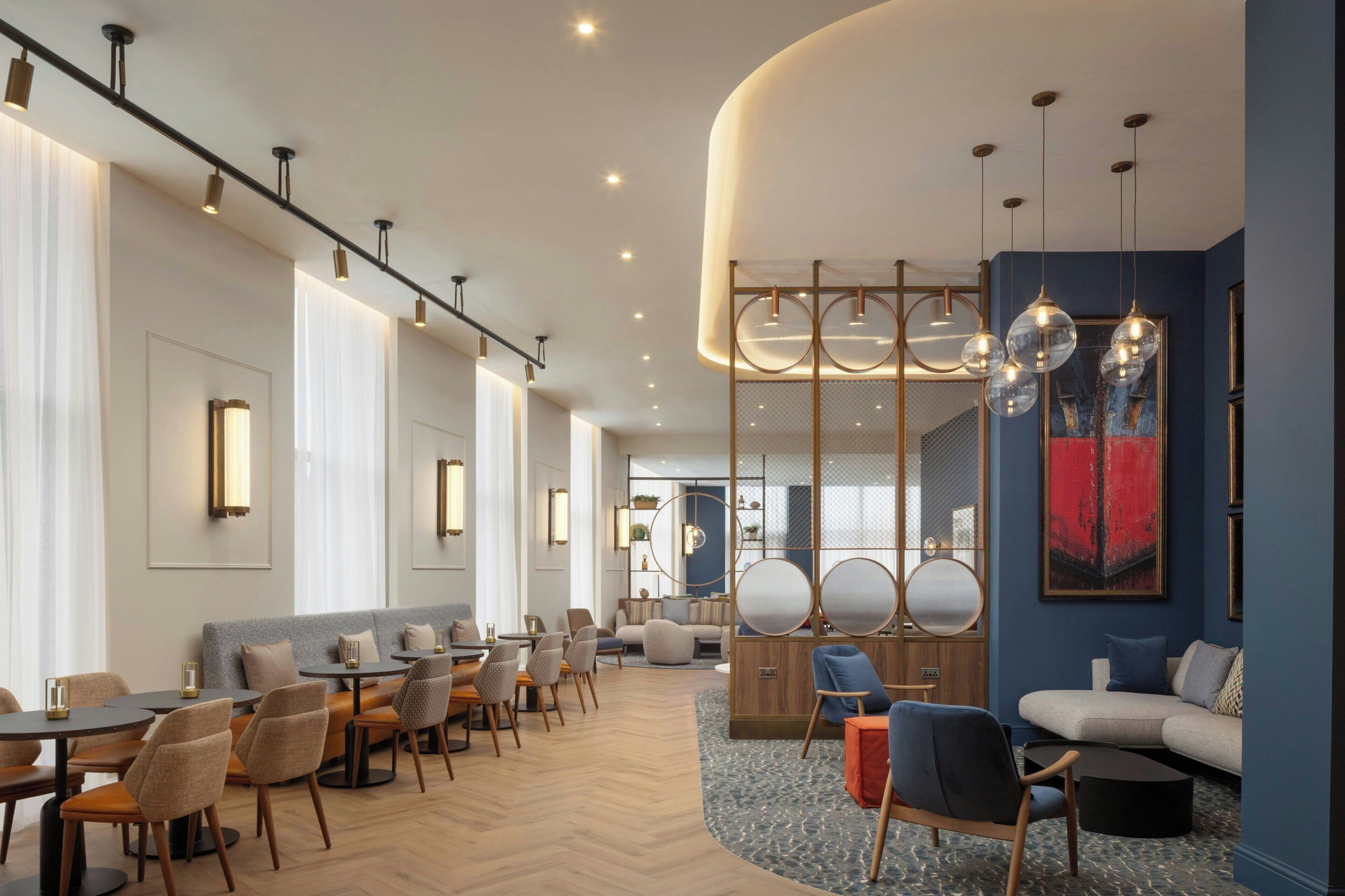 Eine moderne Hotellobby mit Sitzgelegenheit, einer Rezeption und einem großen, abstrakten Gemälde an der Wand.