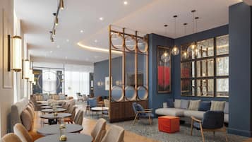 A modern hotel lobby with round tables, sofas, and a large window with artwork.