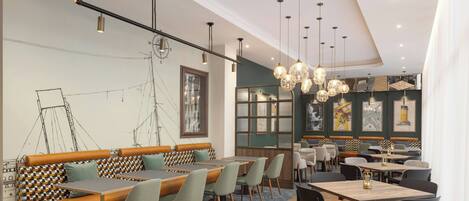 A modern restaurant with wooden tables and benches, pendant lighting, and artwork on the walls.