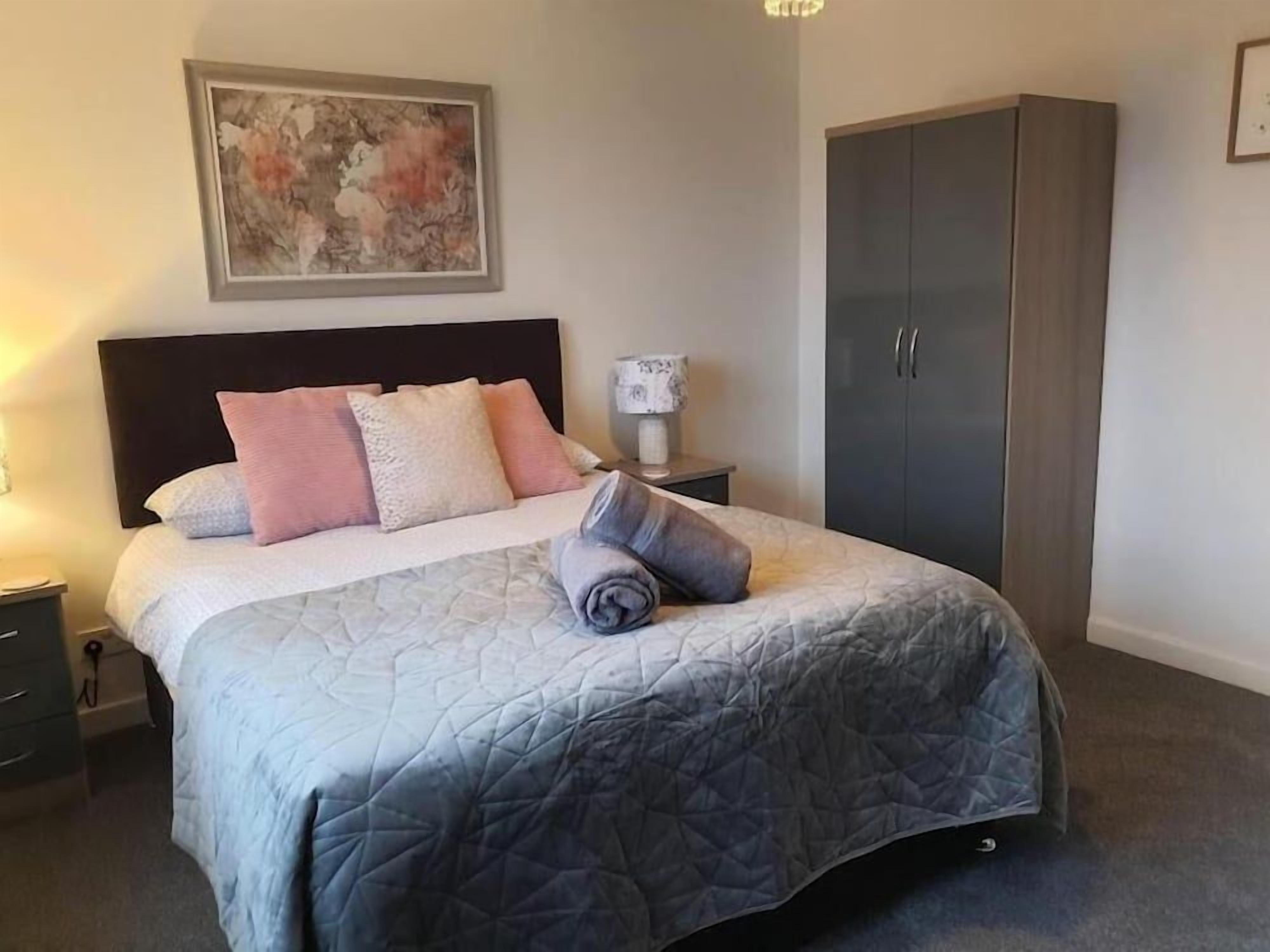 Un lit bien fait, avec une couverture matelassée, une lampe de chevet et une armoire.