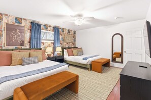 Une chambre d’hôtel avec deux lits, un bureau, un miroir et un mur décoré de motifs.