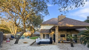 Una casa con jacuzzi, terraza techada y camino de entrada de grava.