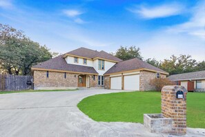 Une maison à deux étages avec un garage, une cour avant et une boîte aux lettres.