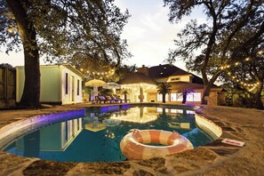 Une piscine dotée d’un espace détente, d’une structure à toit de chaume et de guirlandes lumineuses.